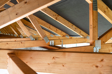 Roof trusses covered with a membrane on a detached house under construction, view from the inside, visible roof elements and truss plates. - obrazy, fototapety, plakaty