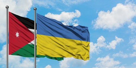 Jordan and Ukraine flag waving in the wind against white cloudy blue sky together. Diplomacy concept, international relations.
