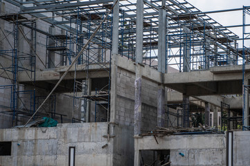 Building and Construction Site in progress. Building construction site against cloudy sky. Metal construction of unfinished building on construction of multi storage building.