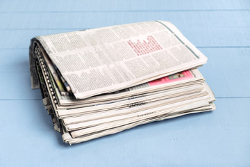 Newspapers folded and stacked on wooden board
