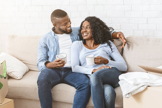 Black couple in love sitting on sofa at new house