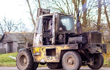 Fototapeta na wymiar worker rides an old forklift, blue smoke comes from the chimney