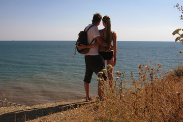 Young couple in love cuddles against the background of an evening sunset over the sea