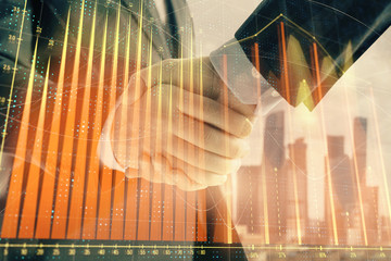 Double exposure of financial graph on cityscape background with two businessman handshake. Concept of stock market deal