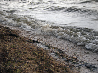 Foam sea wave rolls on the shore, covered with small pebbles.