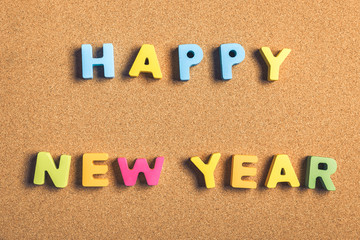 Happy New Year word formed by letter pieces on cork background