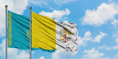 Kazakhstan and Vatican City flag waving in the wind against white cloudy blue sky together. Diplomacy concept, international relations.