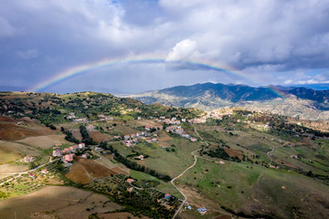 Fototapeta na wymiar View on the valley with typical Sililyan Landscape with fields, mountains, roads and rainbow, Italy
