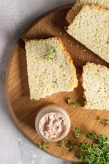Fresh homemade chicken liver pate on bread with thyme on a wooden cutting board. 
