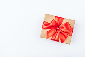 Cardboard gift box with red bow on white background. Flat lay. Top view. Copy space for your text.
