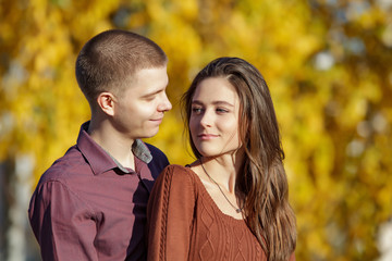 Beautiful young couple in orange autumn leave. Handsome man and attractive woman, love story in autumn park. People relationships.