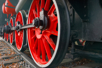 Fragment of a retro locomotive on railway, red wheels of the black locomotive 