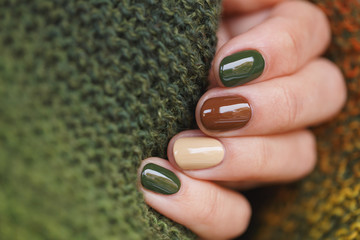 Herfstkleuren manicure op korte ronde natuurlijke nagels met groene gebreide sjaal