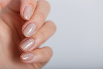 Nude color manicure on short round natural nails on the pure grey background