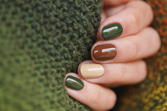 Autumn colors manicure on short round natural nails with green knitted scarf
