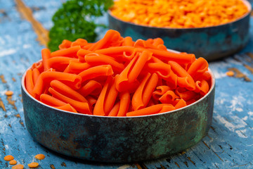 Orange gluten free diet pasta made from lentils  legumes on blue wooden table