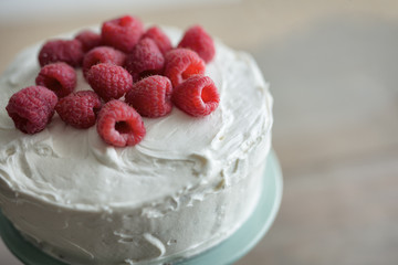 Whole raspberry cake with vanilla icing and fresh berry garnish. 