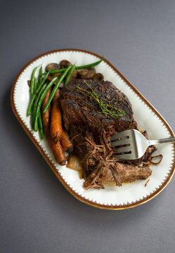 Slow cooked beef roast with carrots and green beans with thyme garnish. 