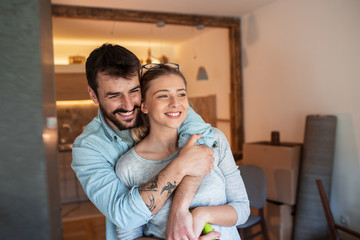 Young couple moving into new home.They standing in living room and embracing each other.