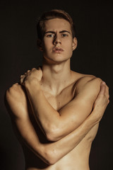 Handsome sport sexy stripped guy portrait with white underwear on isolated black background with colored light