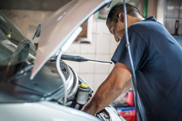 Car mechanic repairer service technician checks and repairs auto engine