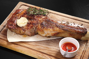 Medium-roasted steak cut into pieces on a wooden board with sauce and seasonings. Delicious steak. Beef steak medium rare on vegetable cushion. Beef steak on wooden plate. 