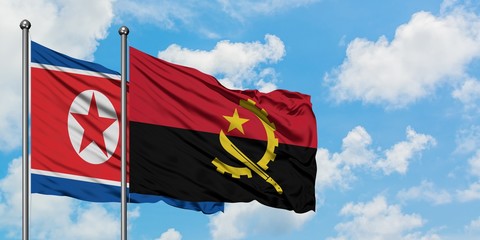 North Korea and Angola flag waving in the wind against white cloudy blue sky together. Diplomacy concept, international relations.