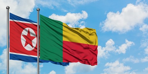 North Korea and Benin flag waving in the wind against white cloudy blue sky together. Diplomacy...