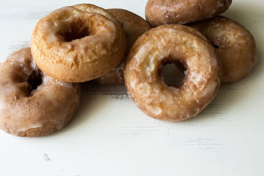 Close up of several plain glazed cake donuts on a vintage painted wood table. 