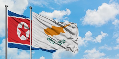 North Korea and Cyprus flag waving in the wind against white cloudy blue sky together. Diplomacy...