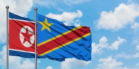 North Korea and Congo flag waving in the wind against white cloudy blue sky together. Diplomacy...