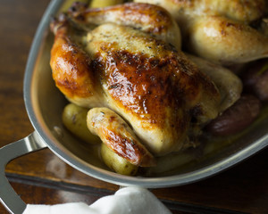 Close up view of Cornish hens, roasted with small fingerling potatoes. 