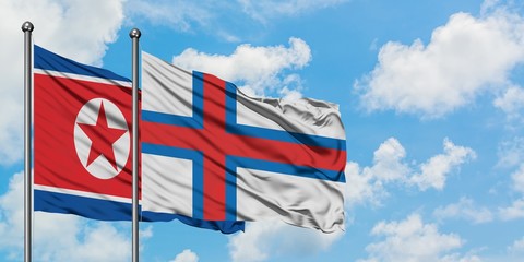 North Korea and Faroe Islands flag waving in the wind against white cloudy blue sky together....