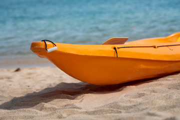 Two colorful orange kayaks on a sandy beach ready for paddlers in sunny day. Several orange recreational boats on the sand. Active tourism and water recreation.