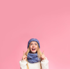 Amazed girl in blue hat pointing up at copy space