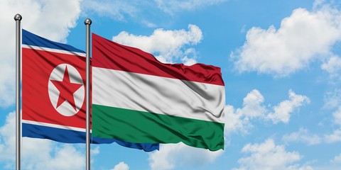 North Korea and Hungary flag waving in the wind against white cloudy blue sky together. Diplomacy concept, international relations.