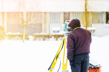 Surveyor engineer uses a total station at a construction site. Geodetic works. Building construction