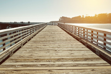 Fototapeta premium Old wood pier illuminated by warm lighting in the Pacific Ocean