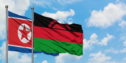North Korea and Malawi flag waving in the wind against white cloudy blue sky together. Diplomacy...