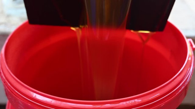 filling a red bin with used waste oil from a deep fryer