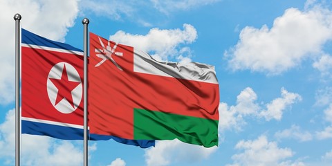 North Korea and Oman flag waving in the wind against white cloudy blue sky together. Diplomacy concept, international relations.