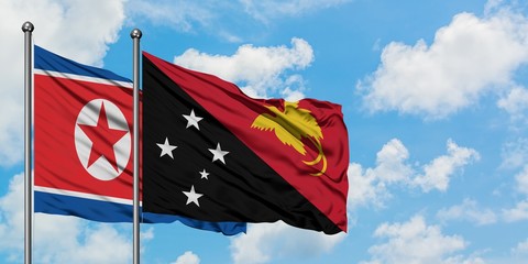 North Korea and Papua New Guinea flag waving in the wind against white cloudy blue sky together. Diplomacy concept, international relations.