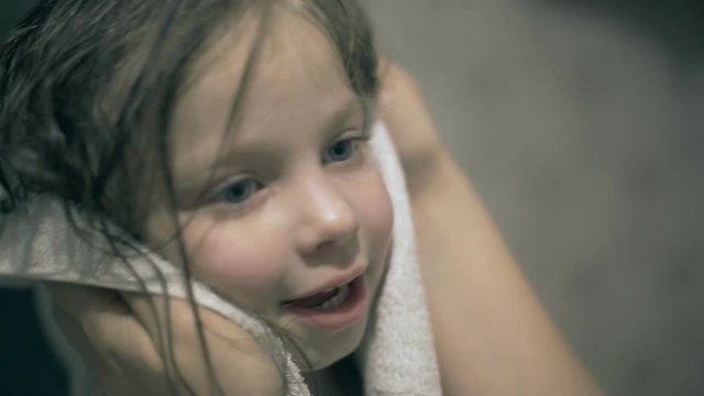 mom wipes her hair with a towel little daughter after bathing