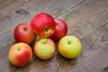 Ripe red apples covered with raindrops on the background of a wooden old table.