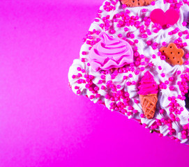 sweet cream with chocolate candies and sponge cake on purple background