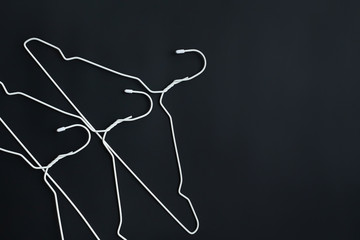 White hangers on black paper background. Minimalistic fashion concept. Sale discount store shopping concept, design empty hanger. Copy space for text.