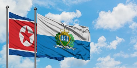 North Korea and San Marino flag waving in the wind against white cloudy blue sky together. Diplomacy concept, international relations.