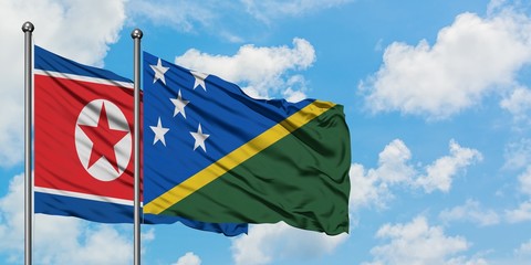 North Korea and Solomon Islands flag waving in the wind against white cloudy blue sky together....