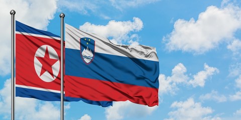 North Korea and Slovenia flag waving in the wind against white cloudy blue sky together. Diplomacy concept, international relations.