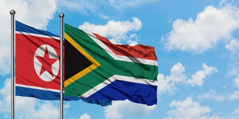 North Korea and South Africa flag waving in the wind against white cloudy blue sky together. Diplomacy concept, international relations.